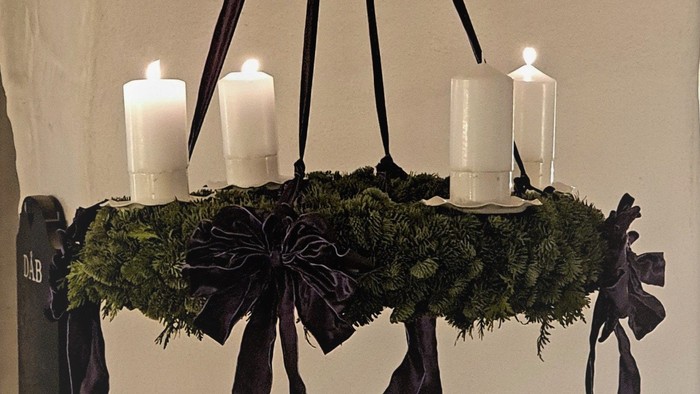 En hængende kandleholder med grønne blomster og sorte bælter.