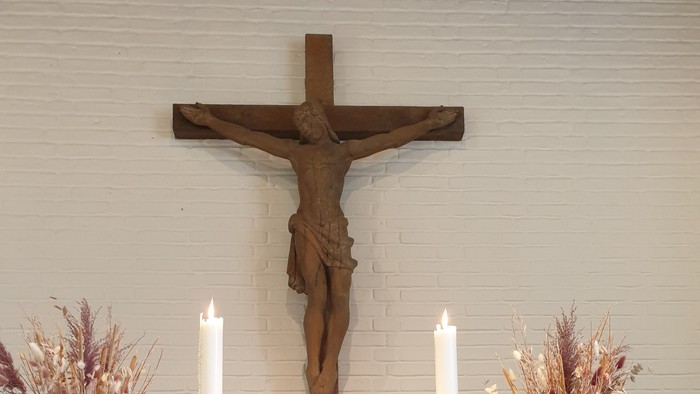 En altertavle med kors, lysestage og blomsterarrangementer