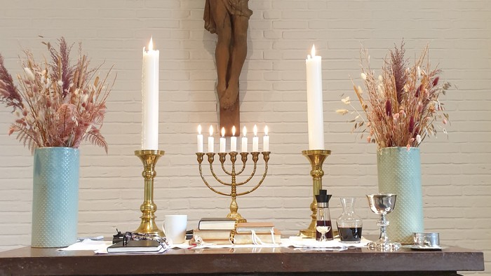 En altertavle med kors, lysestage og blomsterarrangementer