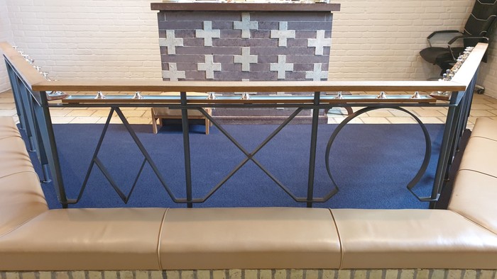 En blå balustrade med sort jernarbejde foran en hvid køkkenbord med sorte og hvide tæpper.