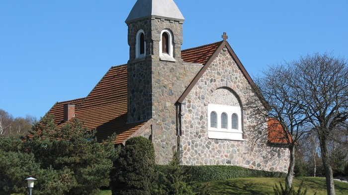 En stenkirke med spids tak og røde tag.