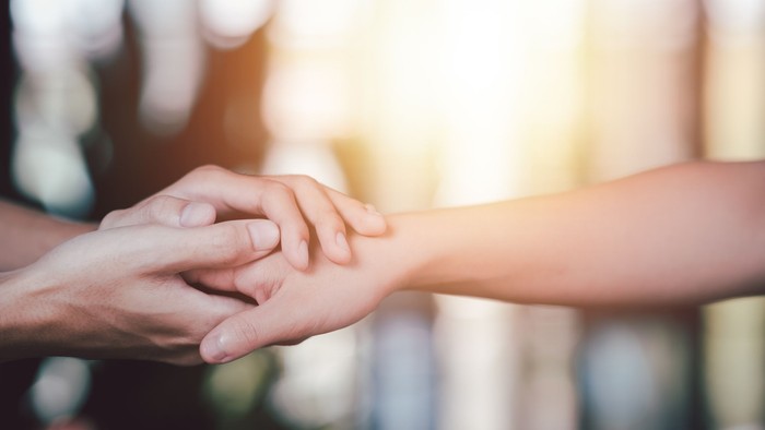 To hands holder hverandre, symboliserer støtte og samarbejde