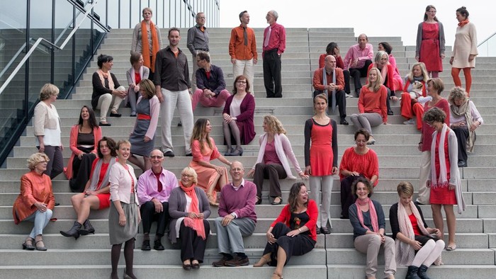 Eine Gruppe von Menschen sitzt auf Treppenstufen, viele tragen rote und weiße Kleidung