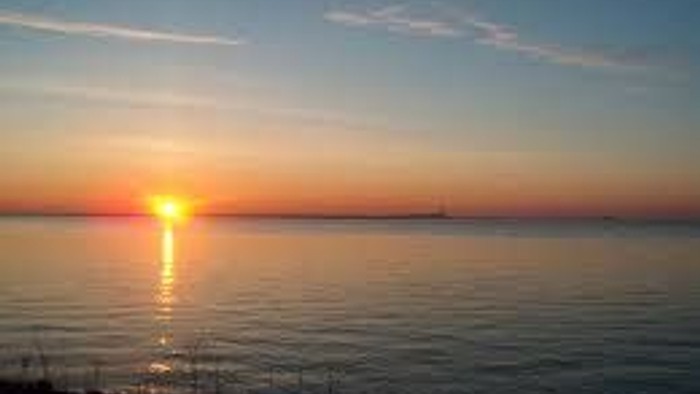 En smuk solnedgang over havet med en skib i horisonten