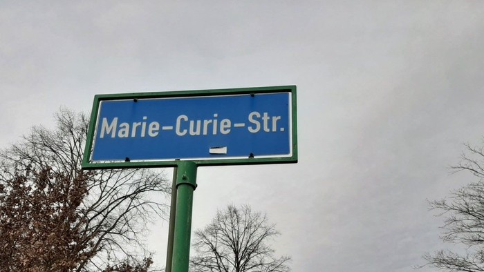 Straßenschild für Marie-Curie-Straße an bewölktem Tag
