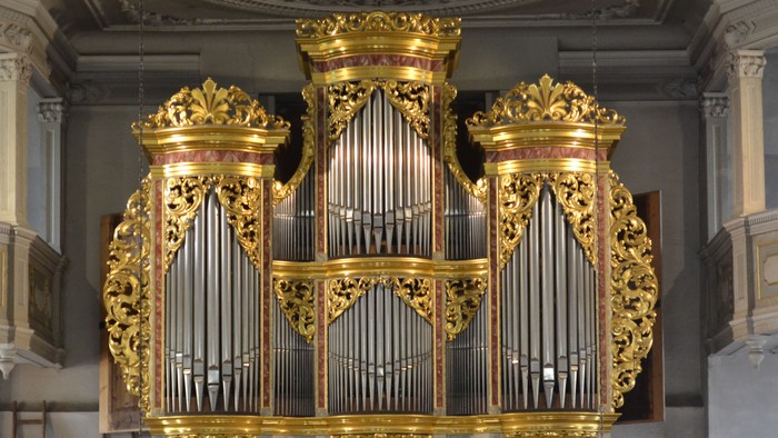 Prächtige, goldene Kirchenorgel in einem großen, verzierten Saal