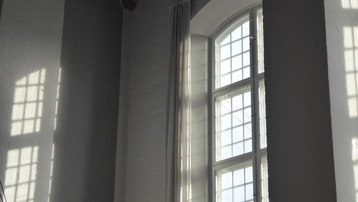 Et rum med store buevinduer og lysende solstråler.