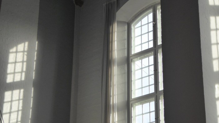 Et rum med store buevinduer og lysende solstråler.