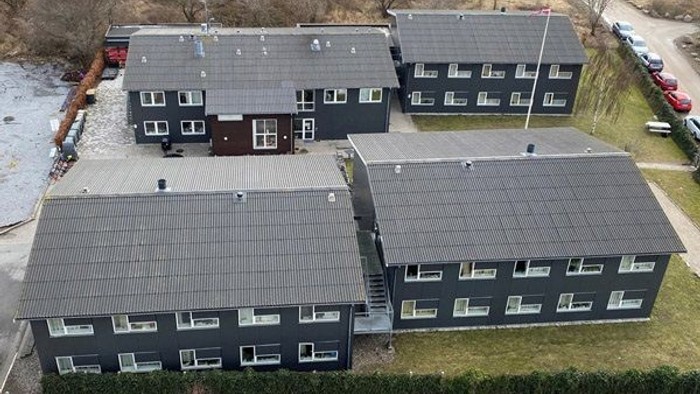 En flyvende oversigt over et stort mørkt boligkompleks med flere bygninger og solceller på tagene