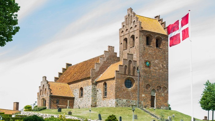 En middelalderlig kirke med en dansk flaggstang foran