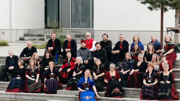 En gruppe af mennesker sidder på trinnene foran et moderne bygning.