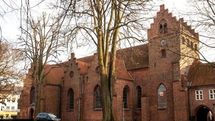 Gamle murstenskirke med tårn og bil foran