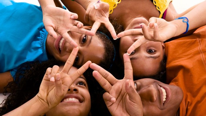 Four people making peace signs with their hands.