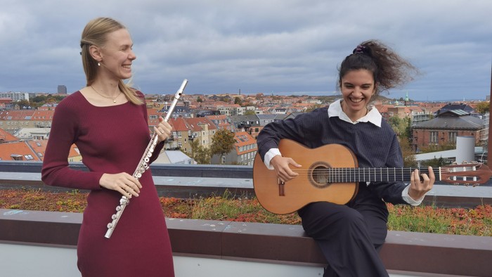 To kvinder poser med musikinstrumenter på en tagterrasse.