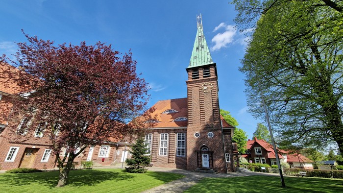Kirchengelände mit hohem Turm und blühenden Bäumen
