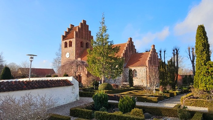 En smuk have med formede hegn og en stor kirke i baggrunden