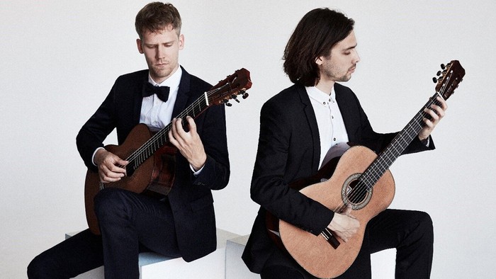 To mænd i formelt tøj spiller guitarer.