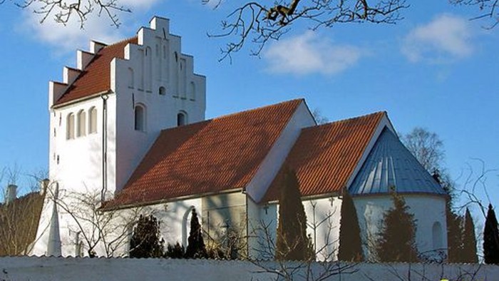 Et hvidt kirkebygning med røde tag og en klokketårn i en snedækked landskab