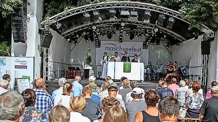 Eine Menschenmenge schaut sich eine Aufführung auf einer Bühne beim Maschseefest an.