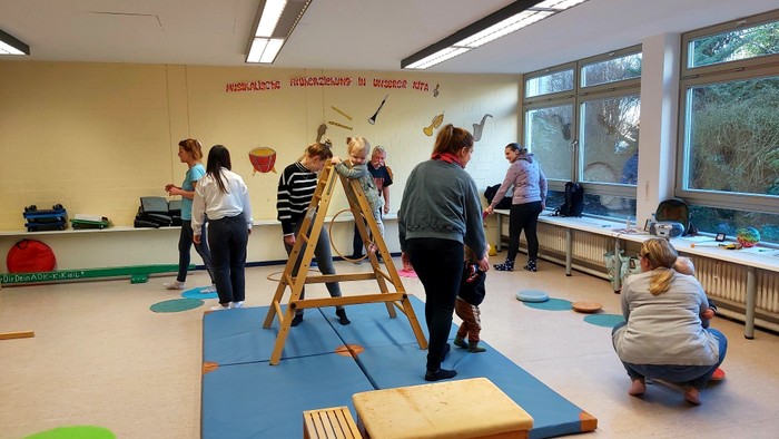 Kinder spielen in einem hellen Raum mit verschiedenen Spielzeugen und Matten.