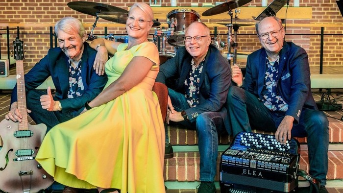 En kvinde og tre mænd poserer med musikinstrumenter