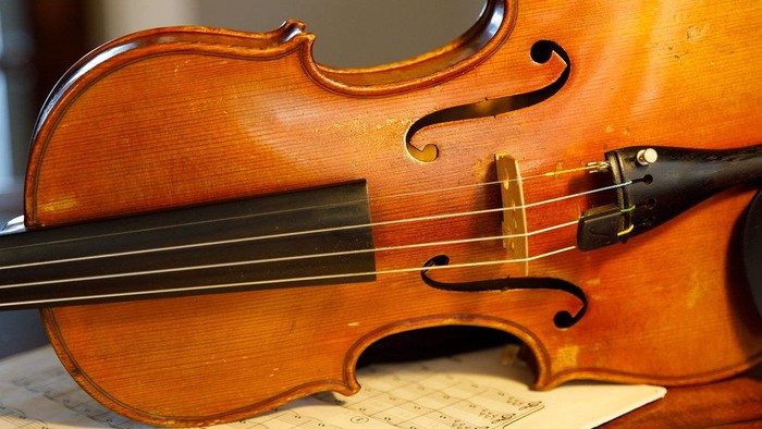 Et brunt violin ligger på noter.