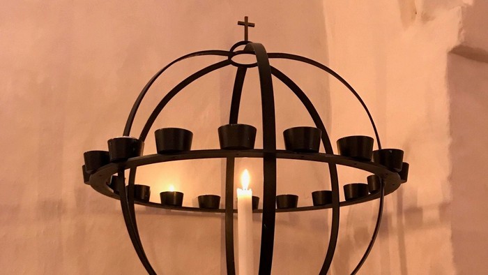 En svart kandleholder med flere lyse candler i en kirke.