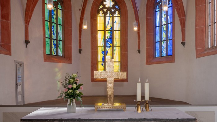 Kirchenaltar mit Kreuz, Kerzen und Buntglasfenstern