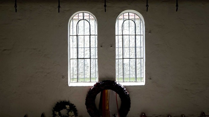 Zwei große Fenster in einem Raum mit Kerzen und Blumen.