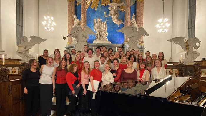 En gruppe af korister samlet foran et orgel i en kirke