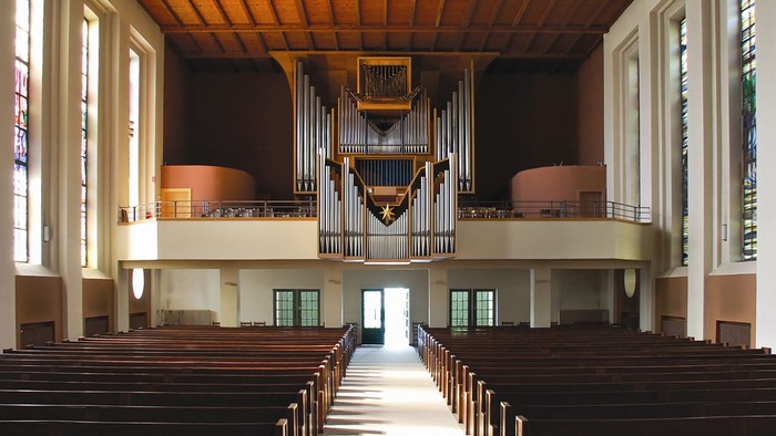 Leere Kirche mit großer Orgel und Holzbänken