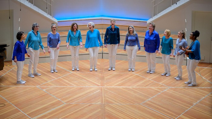 Ein Tanzkurs mit mehreren Paaren in blauen und weißen Outfits auf einem Holzboden