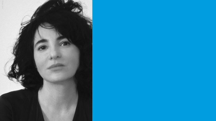 Eine Frau mit dunklem Haar vor einem blauen Hintergrund.