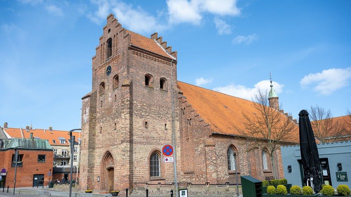 Gamle kirke med teglmur og spistegning i bymiljø