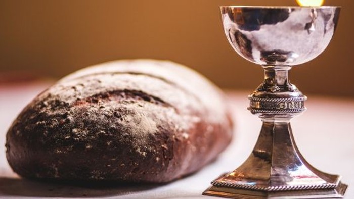 En sølv kalk og en mørk brødstang på bordet