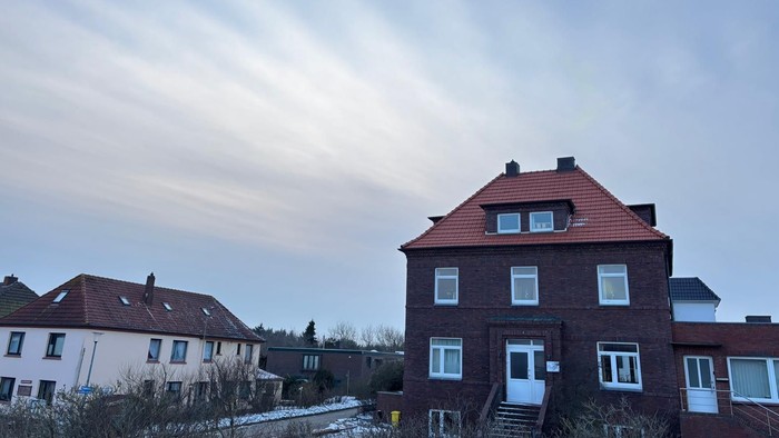 Hier sieht man das Haus Ibbenbüren, ein roter zweigeschossiger Klinkerbau mit roten Dachpfannen.