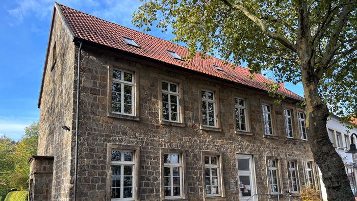 Hier sieht man das Gemeindehaus Alte Schule. Es ist ein zweigeschossiges Sandstein Haus.
