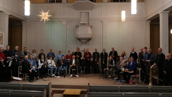 Eine große Gruppe von Musiker:innen, die auf einer Bühne in einer Kirche auftreten.