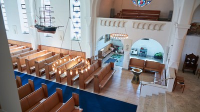 Indre del af kirke med skibsmodel og bænke.