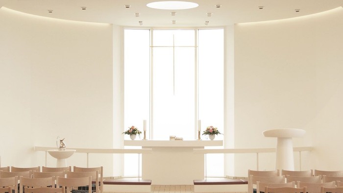 Rundt og lys rum med lang, smuk table og mange stol.