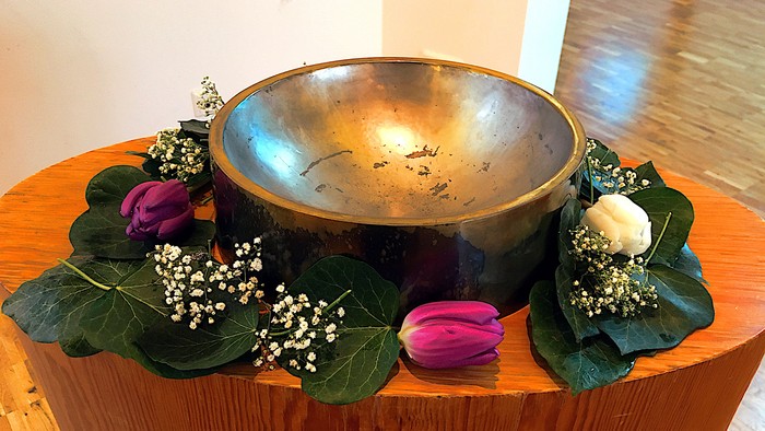 Ovaler Holztisch mit einer Taufschale aus Messing und geschmückten Blumen