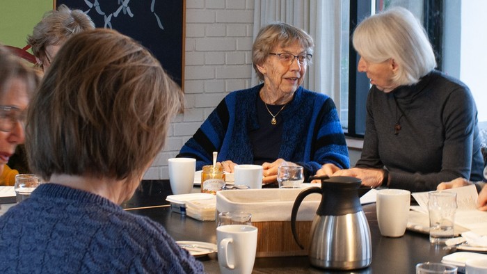 En gruppe pensionister sidder ved et bord i et café og spiser morgenmad.