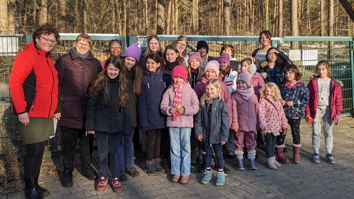 Eine Gruppe von Kindern und Erwachsenen posiert vor einem Zaun im Freien