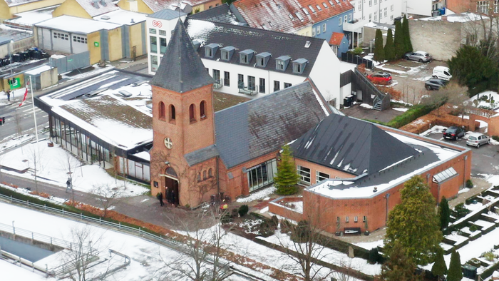 En kirke med tårn i en snedækket by.
