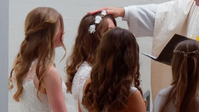 En præst udfører en ritual på et barn, mens andre barn og en voksne kigger til.