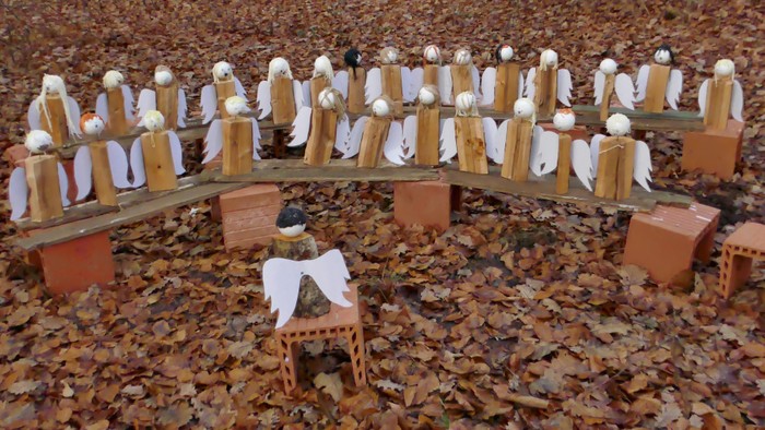 Kleine Holzfiguren, die auf einer Brücke und um sie herum arrangiert sind, umgeben von Herbstblättern.
