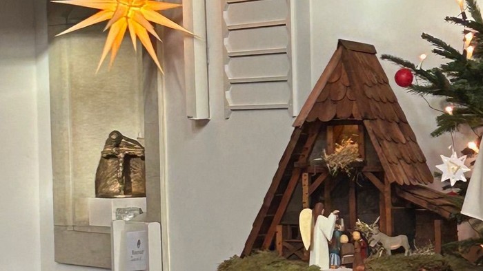 Gottesdienst mit Priester und Kindern in der Nähe einer Weihnachtsdekoration