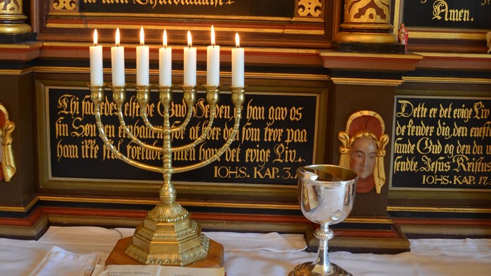 En religiøs stilleben med kandle, bog og drikkeemne