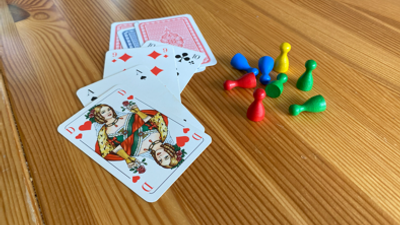 Drei Spielkarten und bunte Spielsteine auf Holzboden