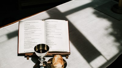 Open book, chalice, and bread on table